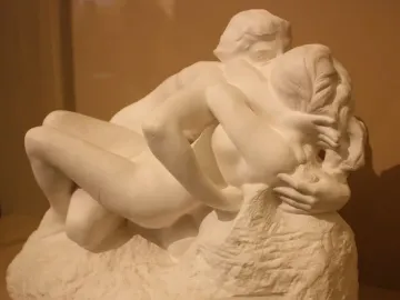 Metamorphoses sculpture of two intertwined nude figures embracing on a rough base