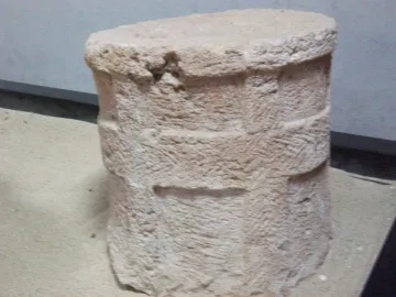 Roughly cylindrical stone section from the Giants of Mont\'e Prama with coarse tool marks and horizontal bands.