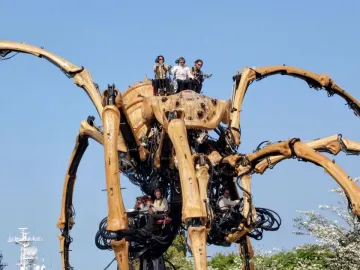 La Princesse, a giant mechanical spider with segmented legs and people operating it beneath a blue sky.