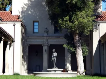 Spirit of Spanish Music, a bronze boy statue holding a long pipe-like instrument in a courtyard fountain.