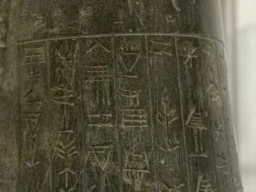 Close-up of the inscribed stone surface of the Idi-Ilum statuette, showing vertical columns of ancient cuneiform characters.