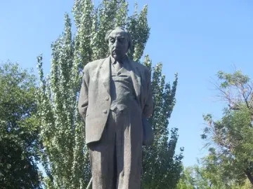Bronze monument to Avetik Isahakyan on a stone pedestal in a park setting.