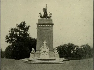 The USS Maine National Monument with sculpted figures and rearing horses on a multi-tiered pedestal in a grassy setting.