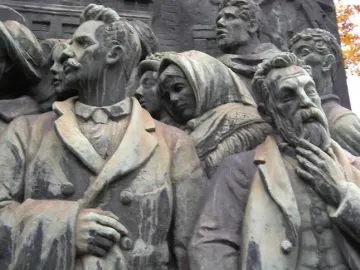Bronze relief on the Branting Monument showing a bearded man in a suit, a mustached man, and a woman in a crowd.