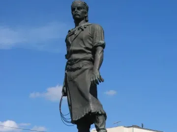 Laçador statue of a gaucho standing on a stone pedestal with a lasso in hand.