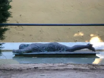 Ophelia Drowned sculpture lying on a platform in a shallow pool of water