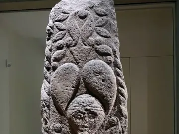 Pfalzfeld Obelisk with carved foliage patterns and three human faces on a stone column.