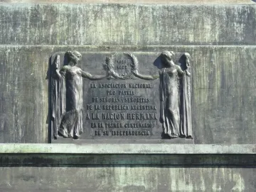 Weathered bronze plaque with two classically draped female figures holding a laurel wreath and an inscription beneath the dates 1822 and 1922.