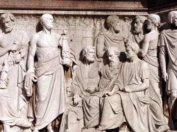 Stone relief from the Frieze of Parnassus showing classical sculptors in draped robes, including bearded figures in profile.