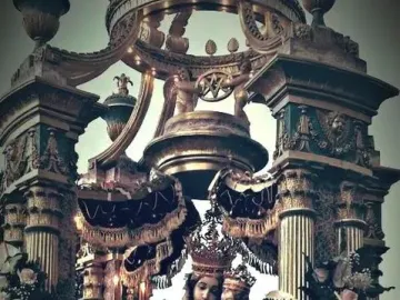 Crowned Madonna dell\'Udienza statue of the Virgin Mary with the infant Jesus, set in an ornate gilded shrine with roses, lilies, and candles.
