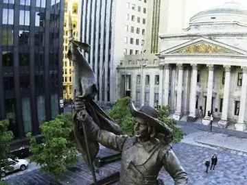 Maisonneuve Monument bronze statue on a stone pedestal fountain in a public square, with high-rise buildings and a domed classical building nearby.