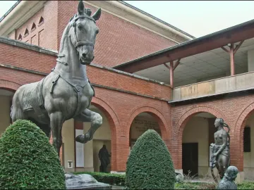 Bronze horse from the Monument to General Carlos M. de Alvear stands in a courtyard with brick arcades and smaller bronze figures.