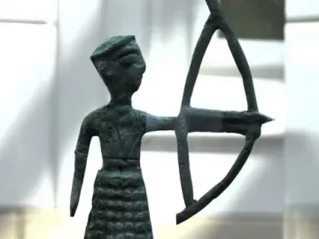 Nuragic bronze statuette of an archer holding a bow on a small base.