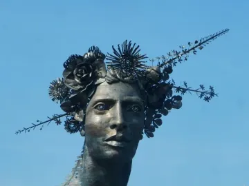 Reminiscencia, a metallic bust with an elongated neck and an ornate crown of metal flowers and spiky foliage.