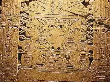 Close-up of the Raimondi Stela showing a stylized face with swirling symmetrical carved patterns.