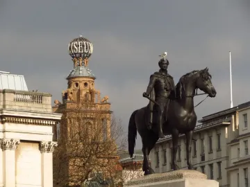 Equestrian statue of George IV on horseback atop a stone pedestal, with a seagull perched on his head.