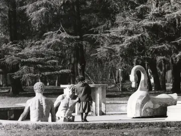 The Mystery Baths sculpture with two submerged human figures and a large swan in a park.