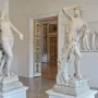 Orfeo y Eurídice marble statues facing each other in a museum room, with Eurydice reaching out and Orpheus holding a hand to his brow.