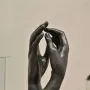 The Cathedral sculpture showing two dark metal hands rising upright with fingertips nearly touching.