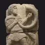 Broken stone relief of the Acrobat from Osuna showing a male figure playing a horn.