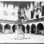 Copernicus Monument in a gothic courtyard, showing a robed statue holding a spherical instrument on a decorated pedestal.