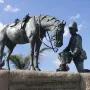 Close-up of the Horse Memorial showing a uniformed soldier in a pith helmet offering a bucket to a saddled horse.