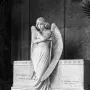 Monteverde Angel marble sculpture standing before the Oneto tomb with wings spread and head bowed.