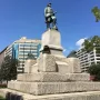 Admiral David G. Farragut statue atop a tall stone pedestal with naval decorations in a park setting.