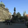 Grunwald Monument with an equestrian statue on a stone pedestal in a city square, with historic buildings and people nearby.