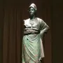 Minerva d\'Arezzo, a green-patinated armored figure standing on a wooden pedestal against a dark backdrop.