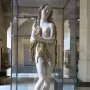 Mary Magdalene sculpture of a standing female figure with long wavy hair, displayed in a glass case.