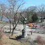 The Falconer bronze statue seen from behind, standing on a stone pedestal with one arm raised.