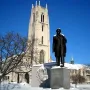 Taras Shevchenko Memorial statue on a snow-dusted pedestal with a church tower behind it.