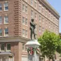 Appomattox bronze statue of a man with crossed arms on a tall stone pedestal in a street