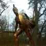 Bronze Greek warrior monument showing a helmeted soldier with a shield and raised sword.