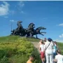 Legendary Tachanka monument with rearing horses and a flag-bearing figure on a green hill.
