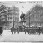 Crowd with umbrellas gathered before the Washington statue in a rainy square lined with ornate buildings.