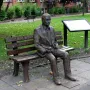 Alan Turing Memorial bronze statue of a man sitting on a park bench holding an apple, with an information board nearby.