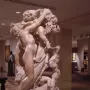 Marble sculpture of A Faun Teased by Children showing a nude faun with children playing around him and holding grapes overhead.