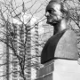Richard Wagner bust on a stone base with his name carved into it, with bare branches and a tall apartment building in the background.