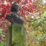 Frederic Chopin bust on a stone base, set against foliage with red and green leaves.