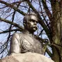 Bronze bust of Józef Piłsudski in military uniform on a stone base against a blue sky.