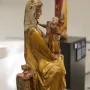 Virgin on a Wide Throne, a weathered wooden sculpture of a seated robed woman holding a child.