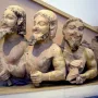 Trisomatos Typhon sculpture showing three male figures joined side by side, with dark traces of beard and hair and faint red pigment.