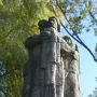 War Never Again stone monument showing a man embracing a woman and child on a tiered base inscribed “NIGDY WOJNY.”