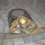 Čumil bronze sculpture of a man emerging from a manhole on a wet street