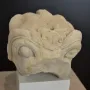 Stone head of the Grifo de Redován with rounded eyes and ornate carved details on the forehead and top surface.