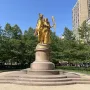 Sherman Monument with a golden equestrian statue on a stone base in a park setting.