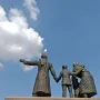 Auswandererdenkmal sculpture group on a tall granite pedestal, with a seagull perched on the central figure\'s head.