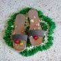 Charan Paduka sandals adorned with flowers on a green mat.